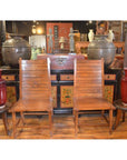 Java teak side chairs with small tables and red vases in front of a decorated cabinet in an antique shop setting.