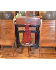 Brown teak side chairs and a small round stool with a red vase, set against cabinets and pottery in the background.