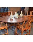 Brown wood Javanese oval dining table with leaf and four matching chairs, styled with decorative blue vases in background.