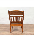 Brown wooden lounge chair with slanted back, viewed from behind on a wooden floor.