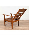 Brown wood lounge chair with slanted back on a wooden floor against a white wall indoors.