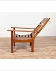 Brown wooden lounge chair with slanted back, side view on wood floor against white wall.