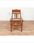 Brown wooden lounge chair with slanted back on wooden floor, color card placed on seat, indoor setting.