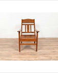Brown wooden lounge chair with slanted back on light wood floor against a white wall indoors.