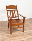 Brown wood lounge chair with slanted back on light wood floor against a white wall, indoors.