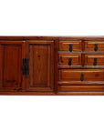 Brown wood jewelry box with one large left door, five right drawers with metal handles, close-up on table.
