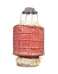 Close-up of a pink wire-wrapped cylindrical lantern with straw accents and metal top, styled like a Chinese paper lantern.