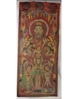 Colorful Laotian parchment painting in double plexiglass frame featuring ornately dressed figure with two smaller figures.