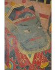 Close-up of Laotian parchment painting showing a stern green-faced figure in ornate robe and headdress.