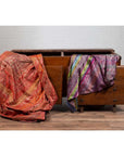 Red and purple fabrics on antique Javanese teak wood chest with iron nailheads, styled indoors.