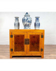 Two-toned burl and elm wood Chinese cabinet with doors, styled with blue and white vases on top, indoors.
