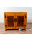 Brown burl and elm wood two-toned patina cabinet with doors, shown on a floor with a color chart in front.