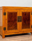 Two-toned burl and elm wood antique Chinese cabinet with doors, placed against a white brick wall indoors.