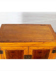 Brown burl and elm wood cabinet with doors, antique style, positioned indoors against a white brick wall.