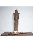 Brown wood Singa Singa Batak tribal carving on table against a white brick wall.