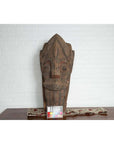Brown hand-carved wooden Singa Singa tribal carving with patterned details from Batak people on table, chart in front.