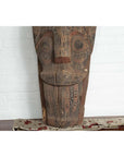 Brown hand-carved wood Singa Singa tribal figure from Batak people, Sumatra, on table with cloth.