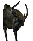 Brown leather gnu sculpture with curved horns and lowered head against a white background.