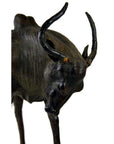 Brown leather gnu sculpture with curved horns and lowered head against a white background.
