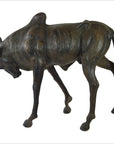 Brown leather wildebeest sculpture with head lowered and legs bent, placed on a plain surface.