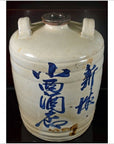 Close-up of a large ceramic sake jar with blue calligraphy and two handles, from Japan Meiji/Taisho period, dark background.