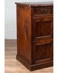 Brown teak wood cabinet with four drawers and four double doors, antique style storage furniture, indoor setting.