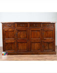 Brown teak wood cabinet with four drawers and four double doors on a wooden floor indoors.