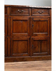 Close-up of a brown teak wood cabinet with four drawers and four sets of double doors, indoors.