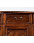 Close-up of brown teak wood cabinet drawer with metal handle; shows four drawers and double doors.