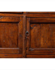 Close-up of brown teak wood cabinet with ring-shaped metal handles and visible wood grain on double doors.