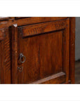 Close-up of brown teak wood cabinet door with metal keyhole, ring handle, double doors, and four drawers.