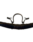 Close-up of a brown leather vintage saddle stirrup and strap next to a large wicker basket with lid on white background.