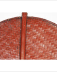 Close-up of a red-brown woven fan with circular design, wooden central handle, and intricate detailing.