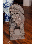 Gray stone lion sculpture, Late Ming Dynasty China, on wooden floor beside blue and white vase indoors.