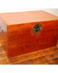 Brown leather coffee table trunk with metal lock on polished wooden floor against a white wall.