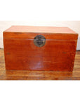 Brown leather coffee table trunk with dark metal latch on wooden floor, white wall background.