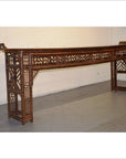 Brown bamboo altar table with geometric lattice design and lacquer finish, placed near a plain wall on wooden floor.