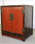 Black and red wood cabinet with ornate doors, brass hardware, and two small drawers at the bottom.