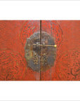 Close-up of black and red wood cabinet doors with gold ornate patterns and antique metal latch.