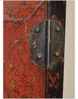 Close-up of ornate metal hinge on black and red lacquered wood cabinet with Chinoiserie finish.