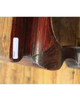 Dark wood square table with curved edge on wooden floor, close-up view.