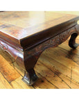 Brown wood square table with carved legs and decorative trim on a hardwood floor.