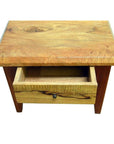 Brown mango wood side table with one front drawer and a partially open brass round pull, indoor setting.