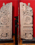 Brown wood Ming Dynasty Chinese temple carvings with figures, floral, and circular motifs on black bases, close-up.