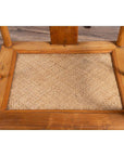 Brown wood and woven rattan close-up of wedding armchair seat on a wood-patterned floor.
