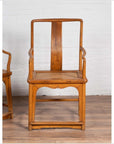 Brown wood and rattan armchairs with curved arms on wooden floor, Ming dynasty style, indoors.