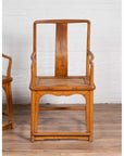 Brown wood and rattan armchairs with curved arms on wooden floor, Ming dynasty style, indoors.