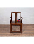 Brown wooden wedding chair with carved medallion and curving arms on wooden floor, color card on top.