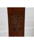 Brown wood chair close-up with carved medallion and curved arms, Ming Dynasty style, blurred background visible.