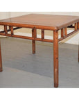 Brown Ming style wood coffee/side table with straight legs and geometric details on a gray floor.
